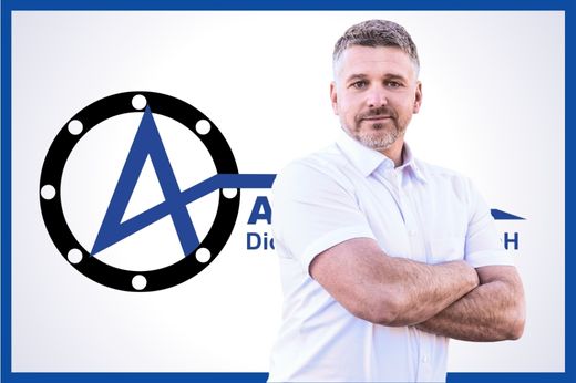 Geschäftsführer Marko Peter in weißem Alpha Dichtungstechnik-Hemd mit verschränkten Armen und freundlichem Gesichtsausdruck vor dem blauen Alpha-Logo auf weißem Untergrund